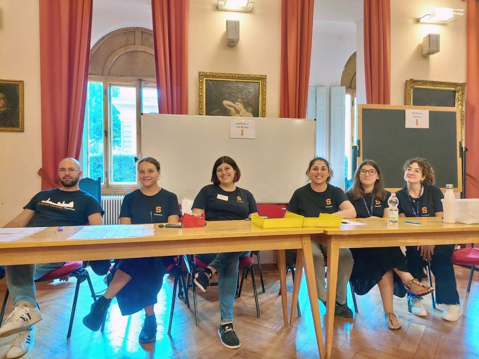 Six staff members pose at a table inside the Daniel and Gayle D'Aniello Syracuse University Program in Florence.