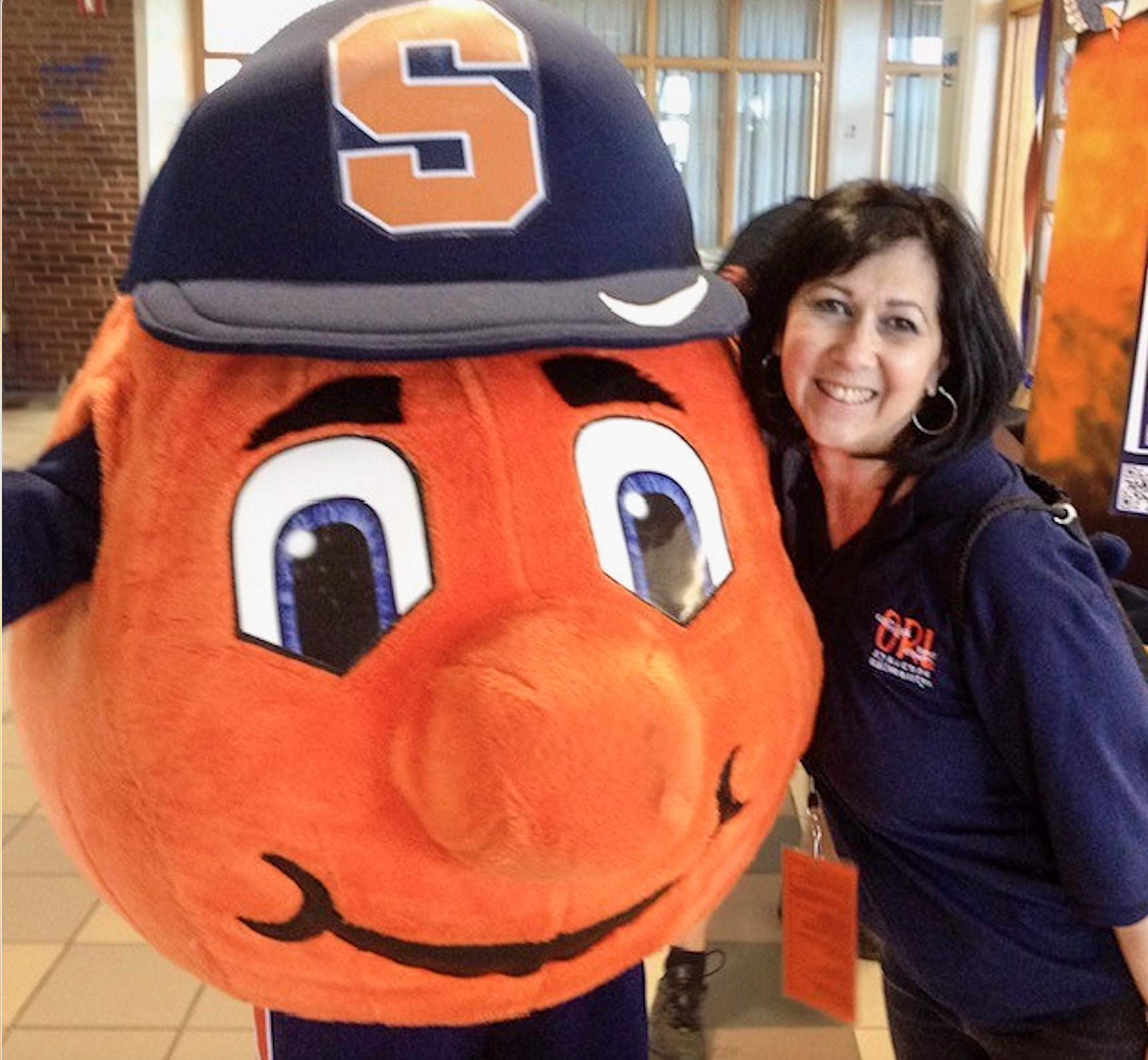 Otto the Orange with a dark-haired woman wearing a blue shirt