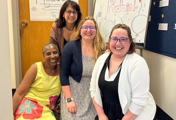 Four women: one in yellow dress, one in black top, one with a black sweater and one with a white sweater