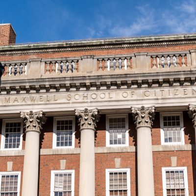 Maxwell School of Citizenship building with red-brick facade, white columns and clear blue sky in the background