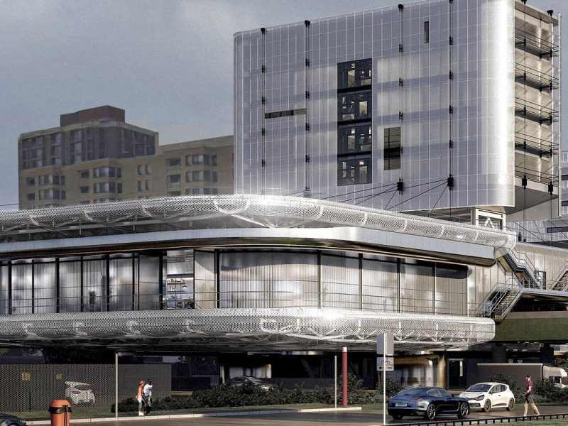 Circular modern building with mesh exterior and glass windows, with two people walking nearby.