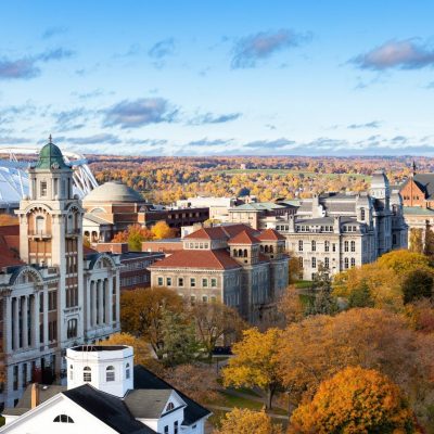 Beautiful blue-sky fall day image of multiple buildings on the University campus, looking at a high level across campus toward downtown Syracuse.