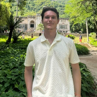 A student smiles while posing for a headshot outdoors.