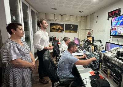 People are standing and seated in a newsroom studio
