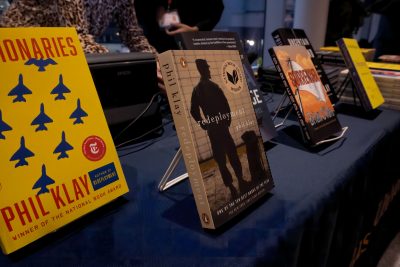 Display of books on stands on a table with a dark tablecloth, including 'Redeployment' and 'Missionaries' by Phil Klay